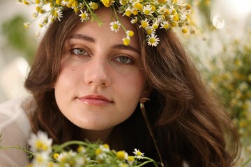 Portrait of beautiful woman with chamomile flowers indoors