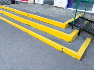 Concrete steps with bright yellow painted edges for safety, captured outdoors in natural light,...