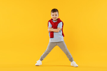 Happy little boy dancing on orange background