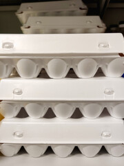 Stacked white egg plastic in a storage space with soft lighting above and below