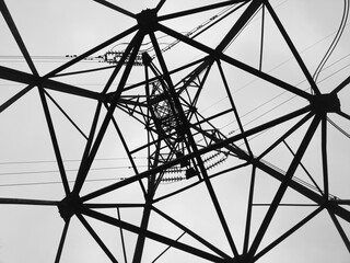 Architectural web of high voltage power lines against overcast skyline clouds
