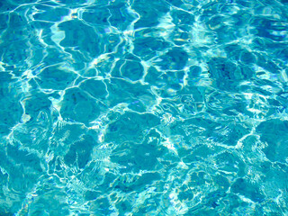 Sparkling blue water with flowing ripples under bright sunlight reflecting light