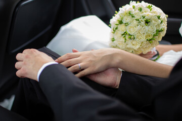Bride and groom holding hands in wedding car