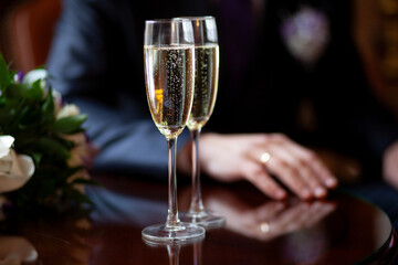 Two champagne glasses on a reflective table