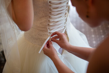 Assisting bride with dressing up in wedding gown