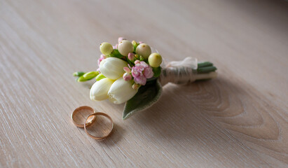 Wedding rings with floral arrangement on wooden surface