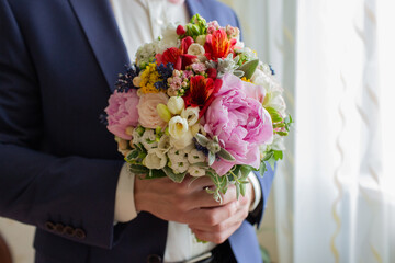 Groom holding colorful wedding bouquet