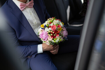 Groom Holding Colorful Bouquet In A Car