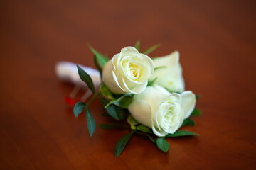 White roses boutonniere on a wooden surface