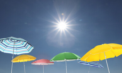 Different bright beach umbrellas against blue sky on sunny day