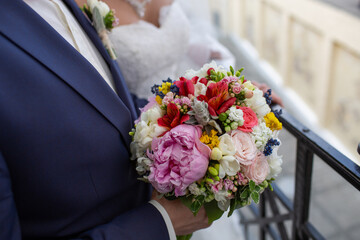 Groom's hands holding a beautiful bridal bouquet