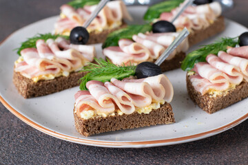 Sandwiches with bacon, cucumber and black olives on toast from rye bread