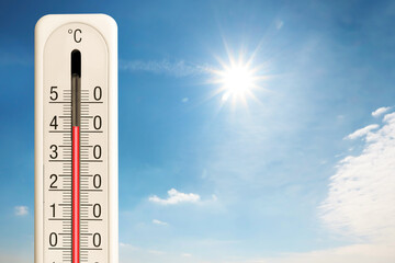 High temperature on thermometer against blue sky on sunny day. Summer weather