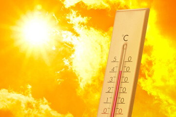 High temperature on thermometer against orange sky on sunny day. Hot summer weather