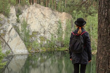 Girl Standing by Cliffside Forest Lake in Outdoor Clothes