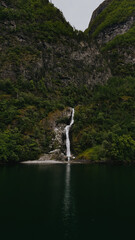 Waterfall in mountains. Clear stream cascading over rocks, lush greenery, peaceful natural scene. 