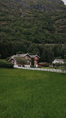 Red house in mountains. Green hills, clear sky, peaceful Nordic landscape. 
