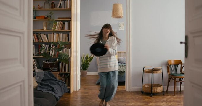 Cheerful girl improvises and dances with nylon plate in her hands in a cozy modern apartment at home. Fun improvisation to nylon music