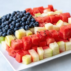 A platter of fruit arranged to resemble the American flag, featuring blueberries, watermelon, and green melon cubes.