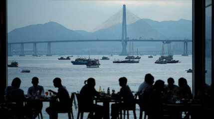 Fototapeta premium People silhouetted at a seaside restaurant in Busan, with views of boats and the Gwangandaegyo Bridge, May 1, 2023