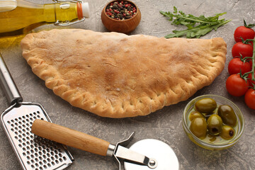 Pizza calzone with basil leaves close up with restaurant background. classic italian food