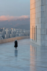 minimalist photograph solitary figure in urban landscape of iran during soft twilight reflecting transition of