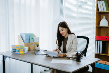 Focused Professional Woman: A smiling young businesswoman efficiently works at her desk,...