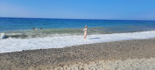 back light shinny portrait of young happy Asian woman relaxed looking at wild sea waves on sunset beach in Kreta Greece enjoying sun and sea breeze in relax holiday and summer vacation trip