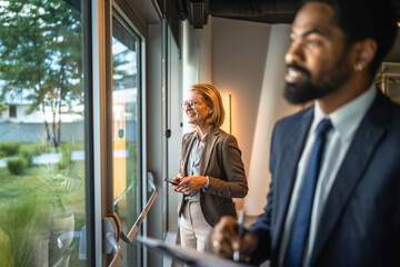 businesswoman use cellphone at workplace while black man stand in front