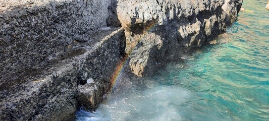 A rainbow emerges when it rains. rainbow with splashing water of a sea. Art of Nature Rainbow in water droplets. 