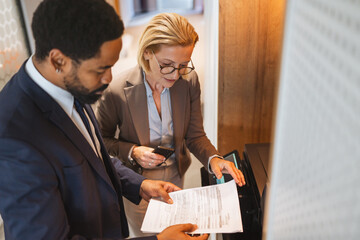 Two multicultural businesspeople talk while scan document on a scanner