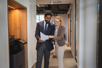 female and male colleague stand by the copy machine and discuss