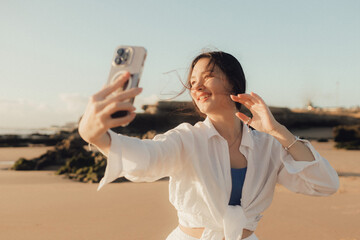 Young girl recording video on phone share via app her travel vacation near seaside. Gen Z...