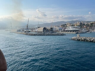 wide panoramic view of the harbor of Genoa. Blue sky blue sea white clouds and port buildings in harmony with the surrounding Mediterranean landscape