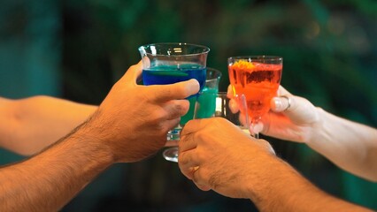 Cropped in couple or group friends making toast cocktail gin tonic, blue hawaii, Cosmopolitan,...