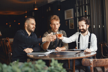 Three bearded men are drinking whiskey and talking.