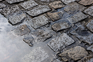Stone floor, sidewalk of a street wet from the rain. Texture with water. Background for projects.