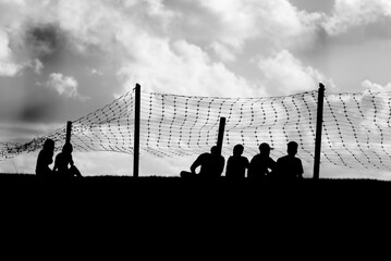 Black and white photo with silhouettes of unidentified people enjoying the beautiful sunset. Late afternoon.