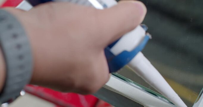 Applying a line of silicone glue to the mirror using a caulking gun.Placing a full tray of coated pork into the oven for cooking.