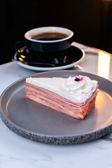 Strawberry Crepe Cake Slice with Cream Topping and Coffee on Marble Table