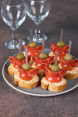 Canapes with sausage salami, cherry tomatoes and green olives
