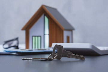 House keys and a stack of dollars with coins and a model house with a calculator. Concept expenses for purchasing a home and financial calculations.