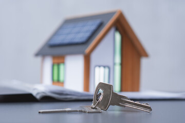 House keys with a model of a modern house with solar panels on the roof. Concept eco-friendly...