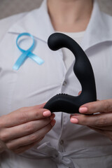 Female doctor holding prostate massager and blue ribbon. Symbol of fight against prostate cancer. 