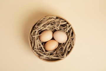 Three brown eggs in paper nest – top view