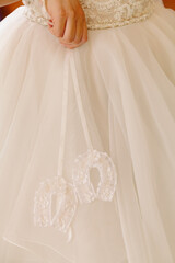 Elegant white wedding dress with intricate details seen during a bridal preparation ceremony in a warm indoor setting