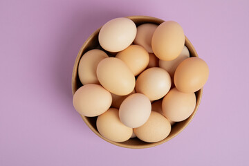 Brown eggs in a bowl – top view on pastel background