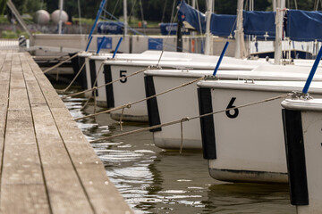 Row of sailboats moored at wooden dock, reflecting in calm water, creating a serene summer holiday...