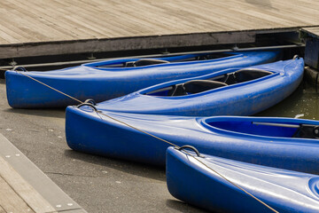 Blue kayaks lined up at the dock, showcasing vibrant colors and reflections in the water, perfect for summer holiday adventures and outdoor activities