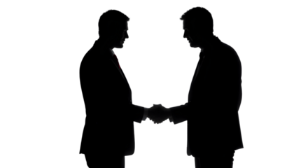 Two businessmen shake hands in a dark silhouette, symbolizing agreement, cooperation, partnership, and a successful negotiation.